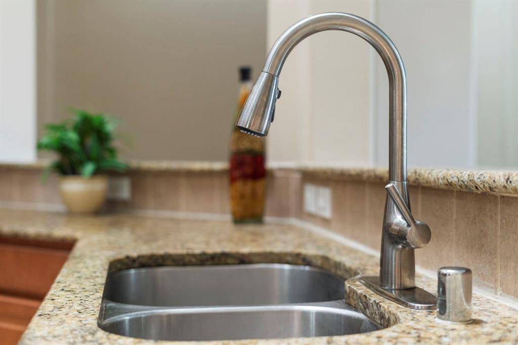 The kitchen features a double stainless steel undermount sink with a sleek pull-down faucet.