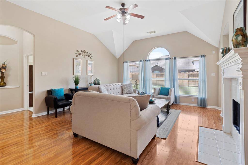The family room, open to the kitchen, features a gas log fireplace and a wall of windows that overlook the backyard, creating a bright and inviting space. With wood floors and a soaring high ceiling, it’s perfect for both relaxation and entertaining.