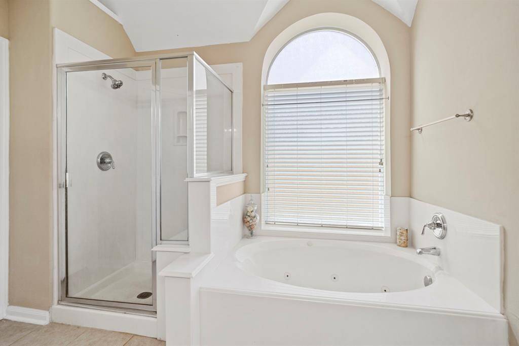 A large arched window fills the owner's bath with soft natural light.