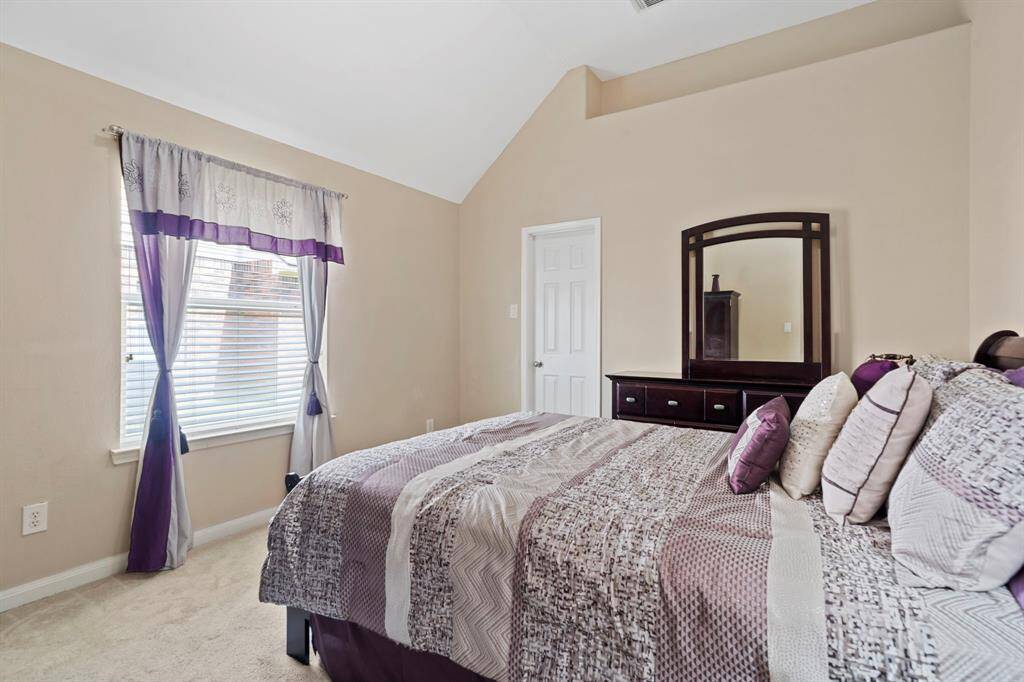 This spacious secondary bedroom offers high ceilings, a large window that fills the room with natural light, and a generous walk-in closet for ample storage.