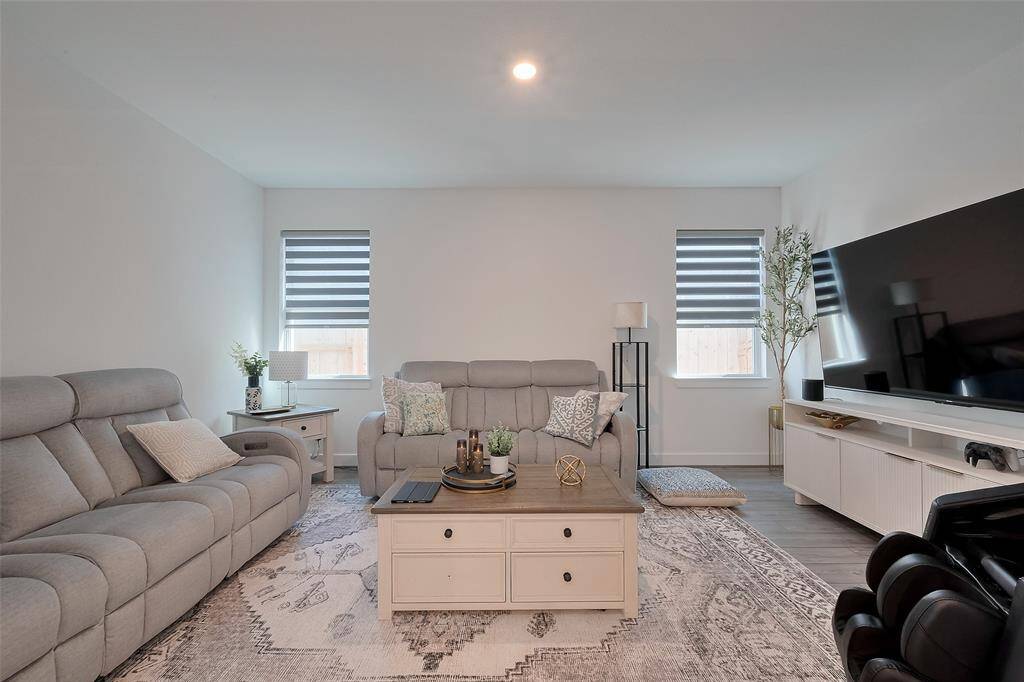 Bright, modern living room with neutral tones.  Ample natural light from two windows with chic blinds, creating a cozy yet elegant atmosphere.