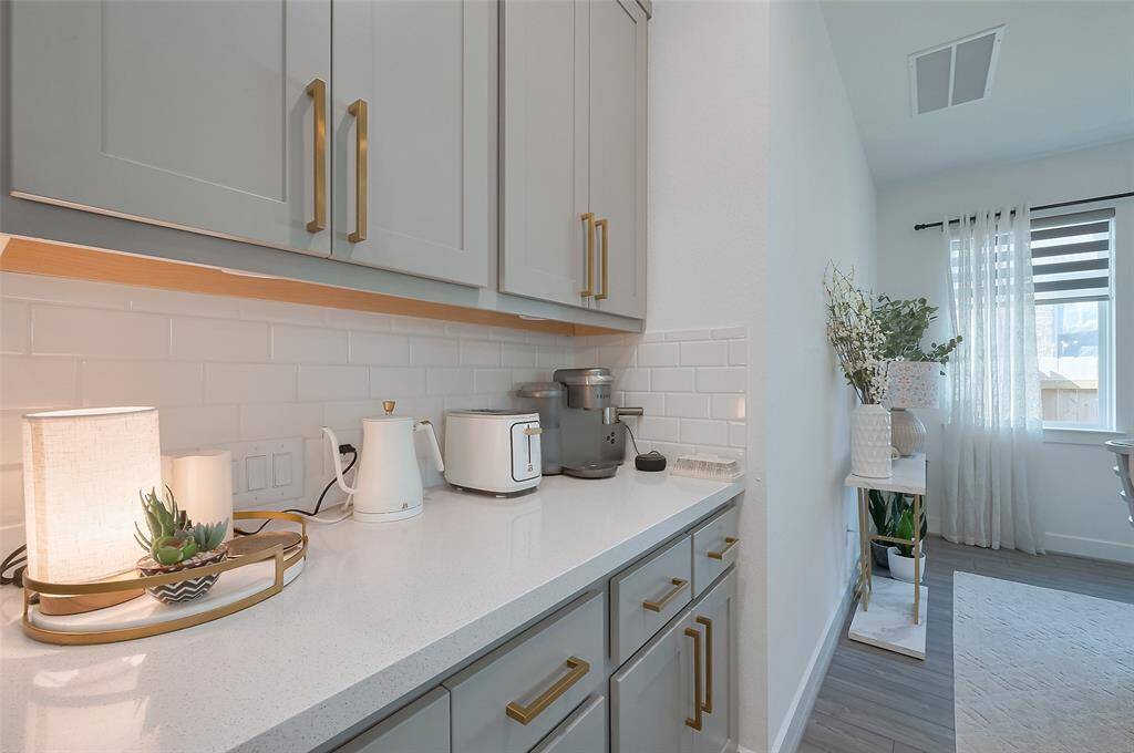 Bright and modern butler pantry space featuring sleek gray cabinets and right next to the dining/breakfast area.