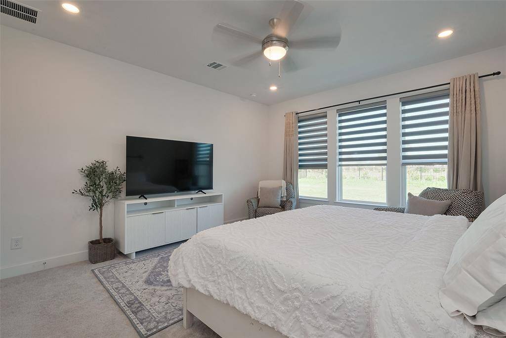 Spacious primary bedroom bathed in natural light, featuring large windows and modern finishes.