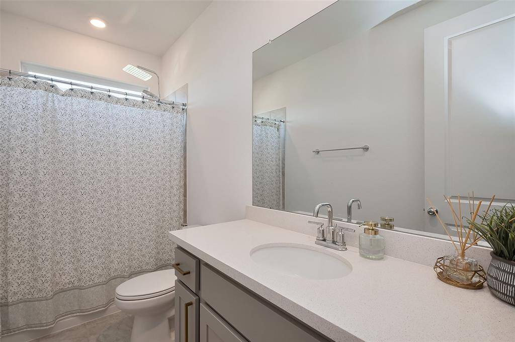 Sleek and modern third bathroom featuring a spacious vanity, elegant fixtures, and a relaxing shower-tub combo. Perfect for unwinding after a long day.