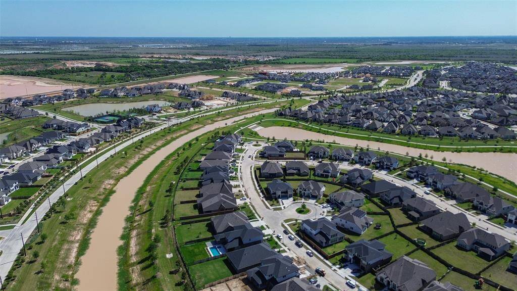 This aerial view showcases a well-planned suburban neighborhood with curving streets, modern homes, and landscaped yards. A waterway and green spaces enhance the community, offering a serene and organized living environment.
