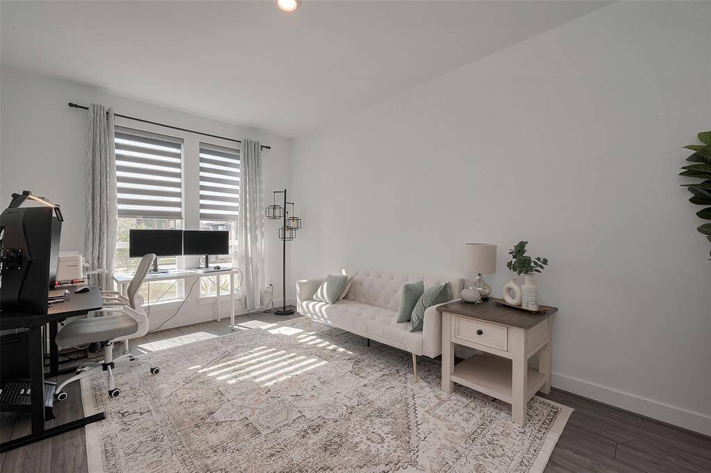 This bright and inviting home office features ample natural light, modern furnishings, and a spacious layout perfect for productivity and comfort.
