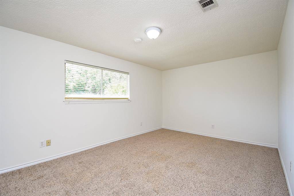 Bedroom 2 features neutral walls and carpet, a ceiling light, and a window with blinds that allows natural light in, creating a bright and versatile living space.