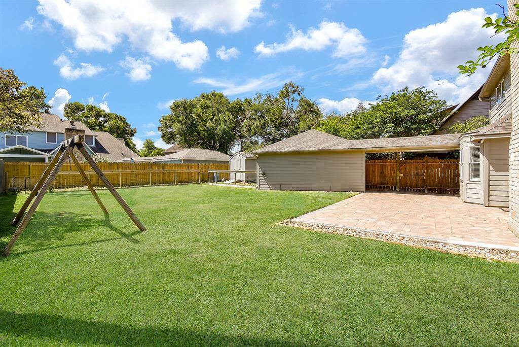 Spacious backyard with well-maintained lawn a large patio area. It includes a fenced perimeter for privacy and a storage shed, ideal for family outdoor activities.