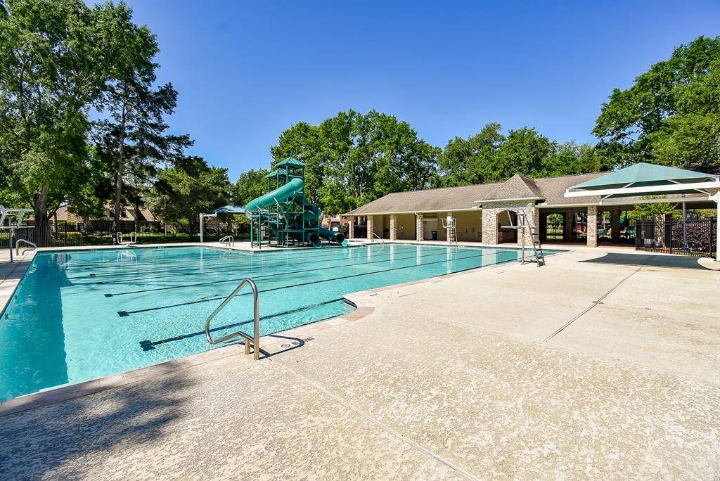 Walk to the neighborhood pool just around the corner! It features a spacious outdoor community pool with a water slide, surrounded by greenery. There’s a covered pavilion and ample deck space for lounging, offering a great recreational area for families.