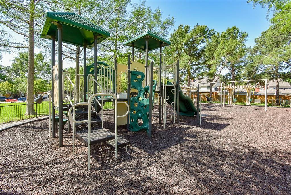 Plenty of playgrounds with slides, climbing structures, and swings. It's surrounded by trees, providing a family-friendly outdoor space ideal for children.