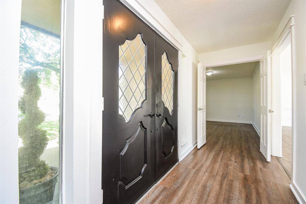 Bright entryway with elegant double doors featuring decorative glass panels. The space opens into a bright foyer with luxury vinyl flooring leading to down stairs flex room (could be a bedroom, media room, office) and Living room.