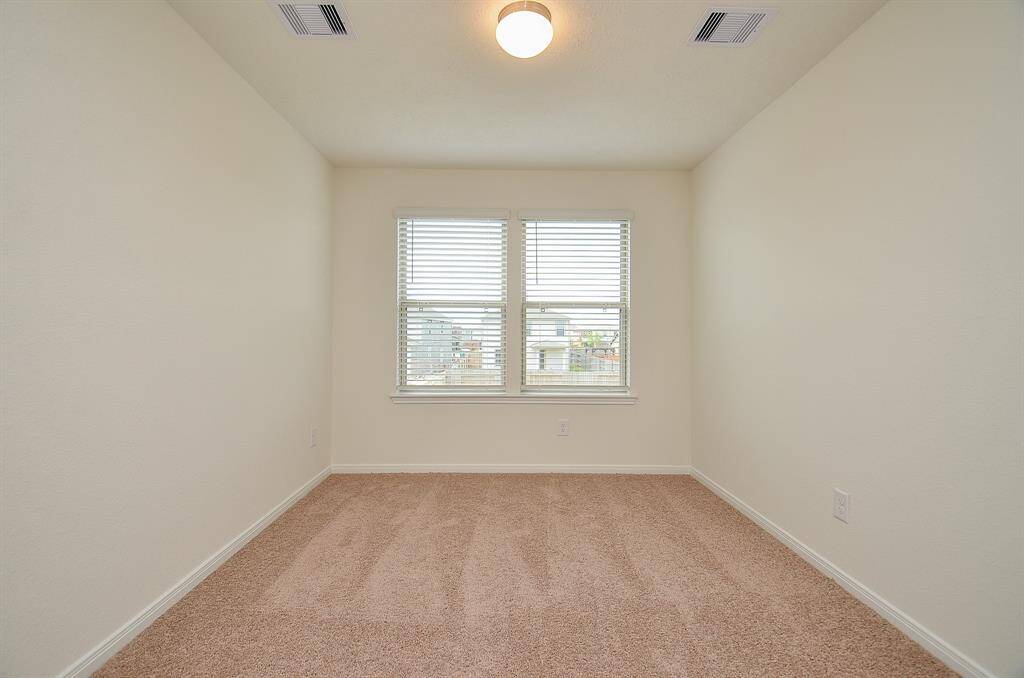 Bright, cozy room with neutral walls and carpet, featuring a window for natural light. Perfect for an office or small bedroom.