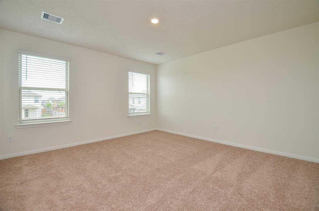 The spacious Primary Bedroom with neutral walls and carpet, featuring two large windows for ample natural light.