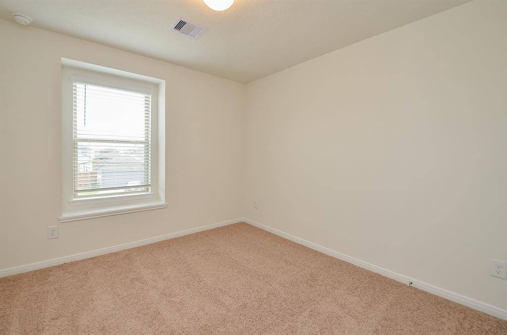 This third Bedroom features a neutral color scheme with soft carpet flooring and a window that provides natural light.