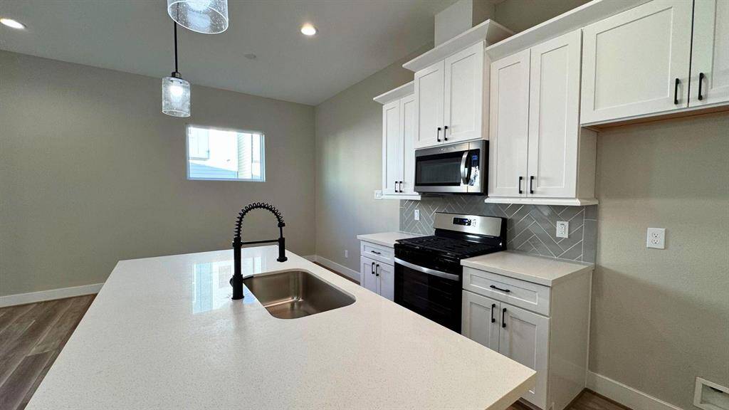Island in kitchen has a sink with beautiful sleek counters.