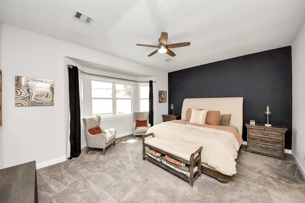 Spacious primary bedroom features bay windows that overlooks the backyard oasis.