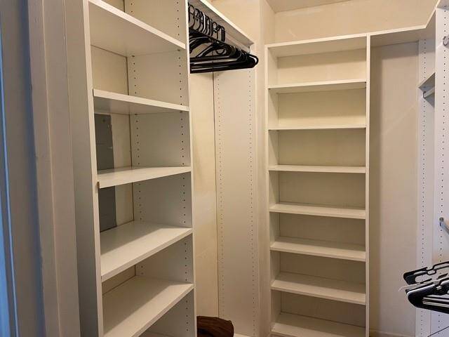 Spacious walk-in closet with built-in white shelving and ample hanging space.