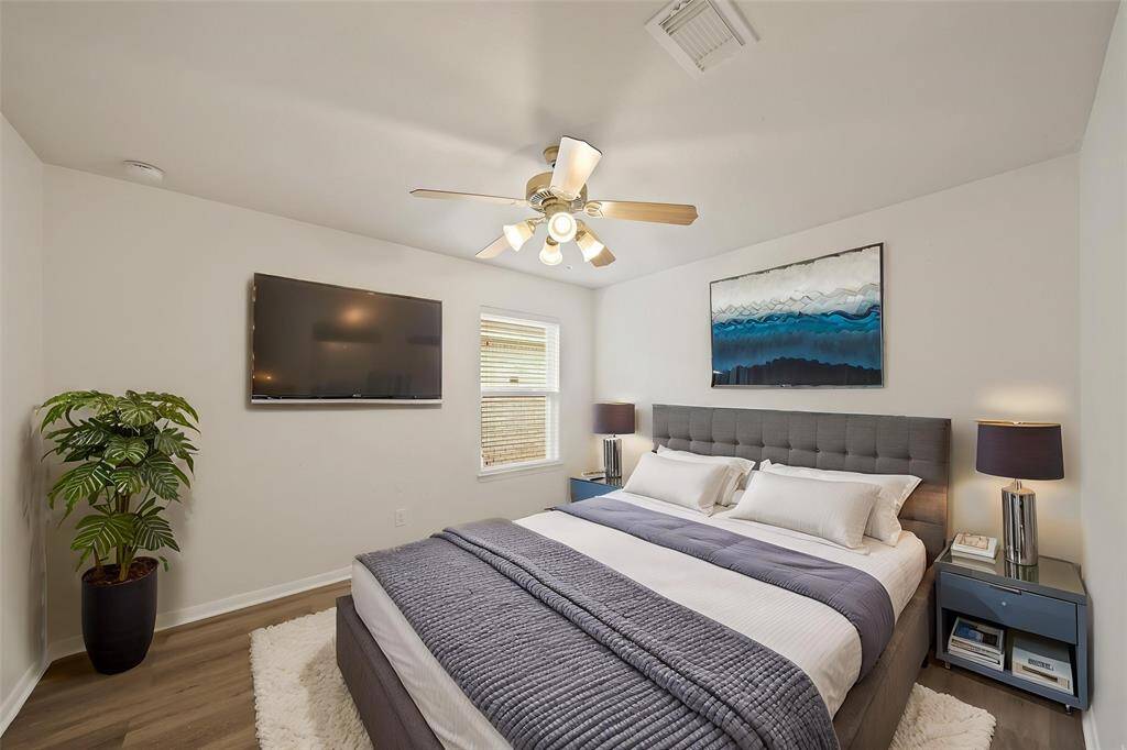 Virtually Staged: Lovely secondary bedroom complete with neutral paint, wood floors, a ceiling fan, and a window with privacy blinds.