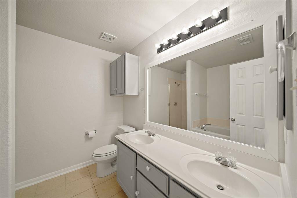 The spacious Primary Bathroom features tile flooring, a tub and a shower, granite countertops, large framed mirror, vanity lights, and his/her sinks with modern finishes!