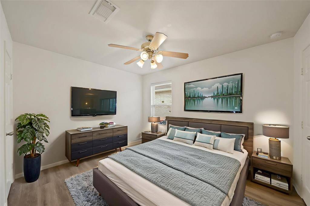 Virtually Staged: Lovely secondary bedroom complete with neutral paint, wood floors, a ceiling fan, a built-in closet, and a window with privacy blinds.