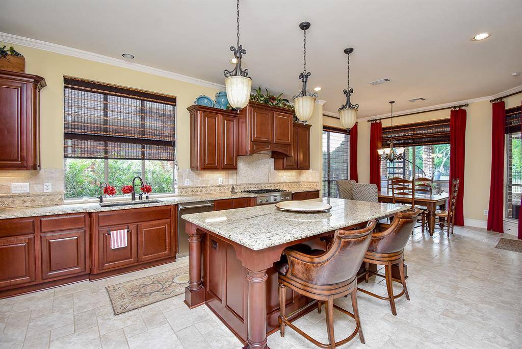 Gourmet kitchen has plenty of counter space and cabinetry. Large island, custom shades & breakfast bar. Crown molding is continued through the kitchen and breakfast room.