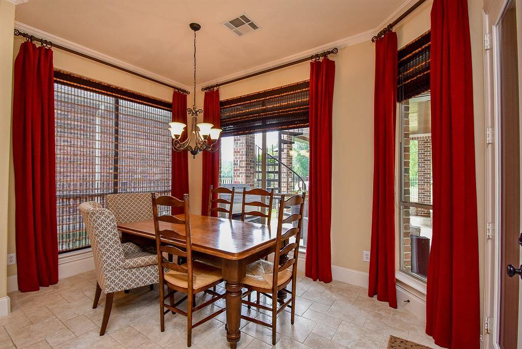 The breakfast room is surrounded by windows providing views to the yard and pool.