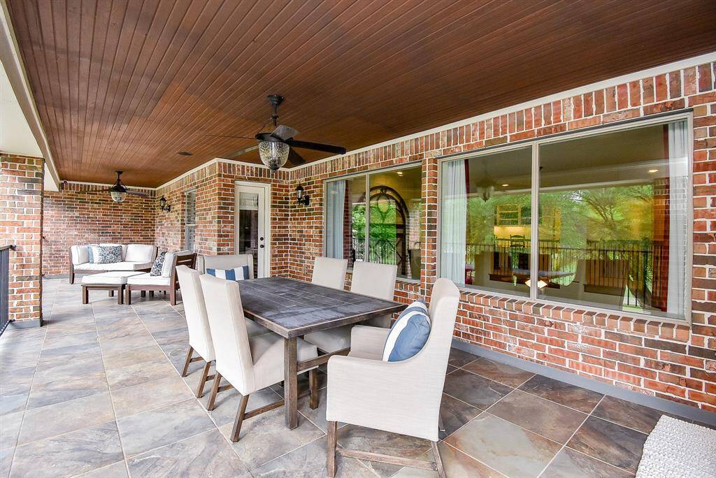 Upstairs covered balcony with tile flooring has plenty of seating and dining area.