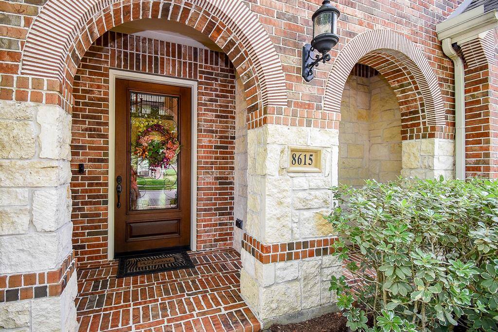 Bricked porch is welcoming. The glass and iron door provide a nice contrast.