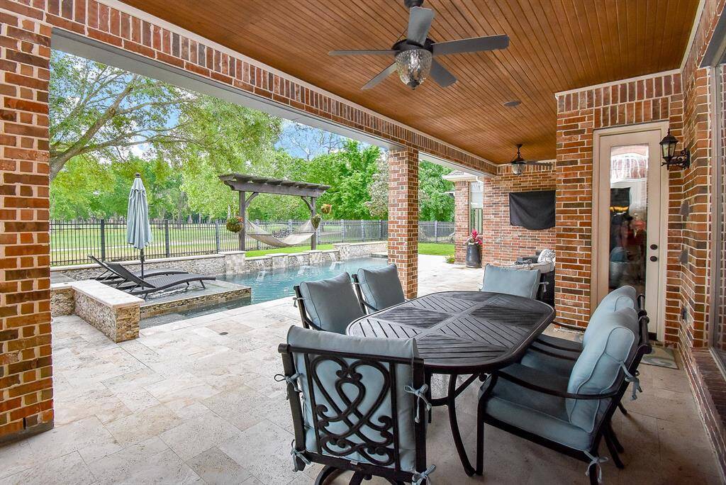The covered patio is accented with travertine tile which adds a touch of elegance to the pool area. The bead board ceiling is a nice effect.