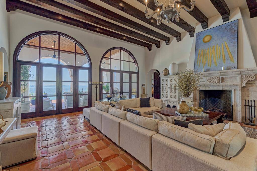 Living room with a statement custom fireplace, rich wood beams, and beautiful views of the backyard.