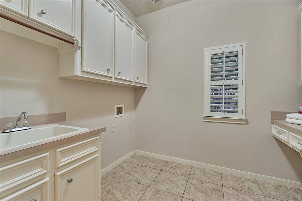 The laundry room has a utility sink, countertop for folding clothes and ample storage.