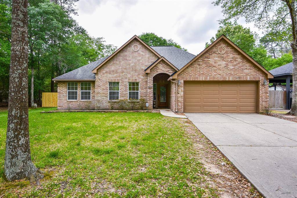 Wide open, airy, wooded space surrounds this special 1-story, brick home, at 919 Fairbanks Drive, Magnolia, TX, in the Cimarron Country community. Pictured here is the attached garage and welcoming driveway.
