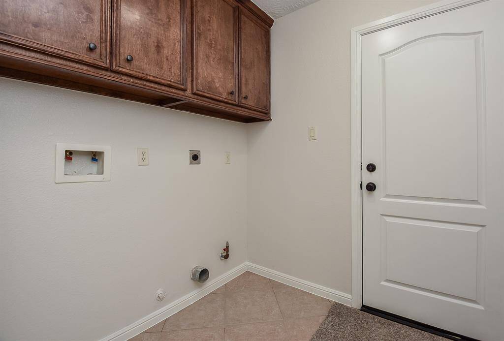 The utility room is bright and tidy and ready with hook-ups for dual laundry appliances, with handy storage above.