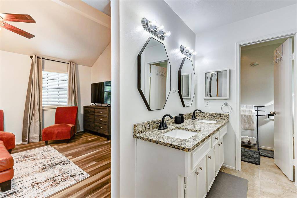 Elevate your daily routine in this elegant primary bathroom, featuring dual sinks with granite countertops, chic lighting, and ample storage.