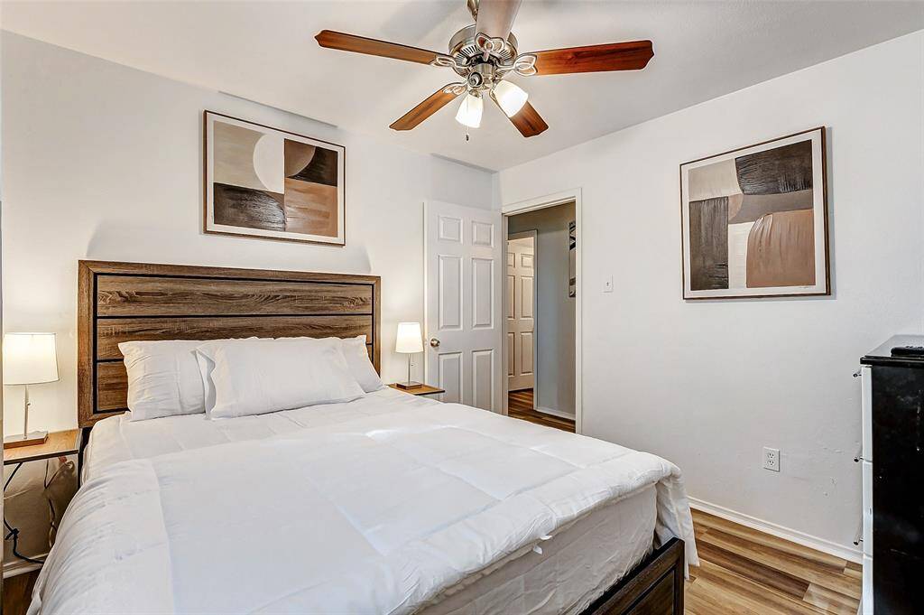 Cozy second bedroom featuring elegant  flooring, modern ceiling fan, and stylish decor—perfect for relaxation.