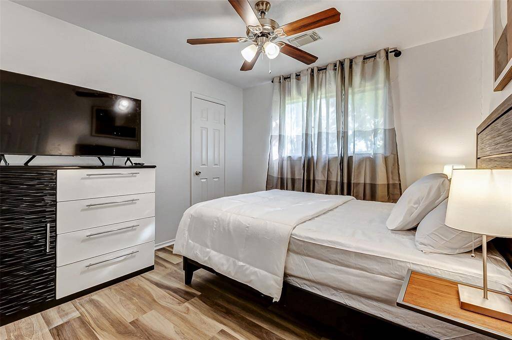 Cozy and bright, Bedroom 2 features a ceiling fan, ample natural light, and a sleek dresser with a mounted TV for ultimate comfort and convenience.