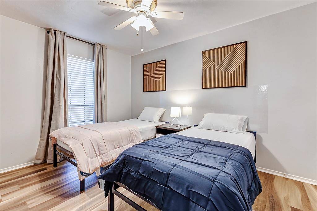 Cozy and inviting, this bedroom features ample natural light, sleek flooring, and a modern ceiling fan—perfect for relaxation.