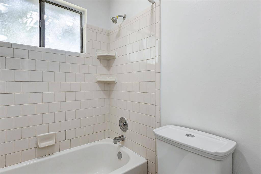 Bright and inviting bathroom with a sleek bathtub, classic tile, and ample natural light.