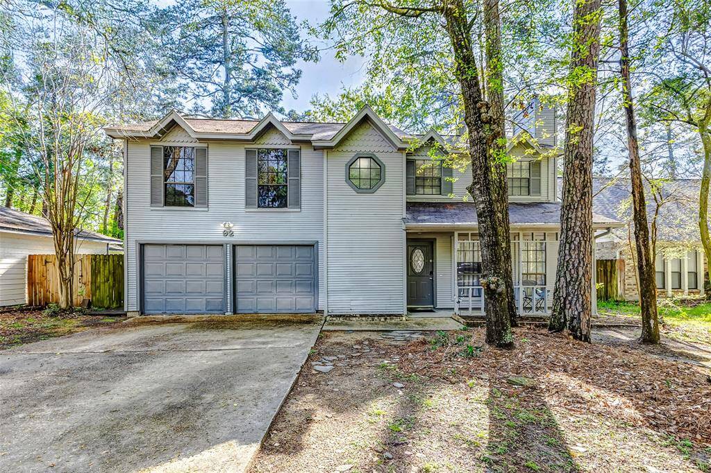Charming two-story home with a double garage, surrounded by mature trees. The front features a symmetrical design with large windows and a welcoming entrance. Set in a wooded area, it offers a peaceful, natural setting.