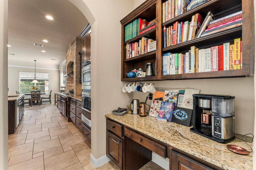 Perfectly positioned between the kitchen and dining room, the butler’s pantry offers both style and function. This convenient space includes a built-in desk area with granite counters for planning or organizing, ample storage cabinets, drawers, and open upper shelving—ideal for displaying glassware or keeping essentials within easy reach. It's the ultimate blend of charm and practicality for the busy chef.