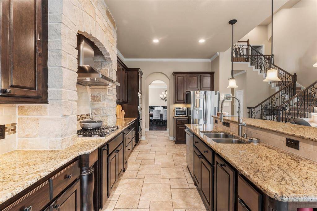 A pristine showcase of elegance and function, this extraordinary kitchen features top-of-the-line stainless steel appliances, including a 5-burner cooktop with stainless steel vent hood, double ovens, microwave, and dishwasher with third rack. Rich Kentmore wood cabinetry offers abundant storage, complemented by sleek granite countertops. Designed for both gourmet cooking and sophisticated entertaining, this kitchen is truly the heart of the home.