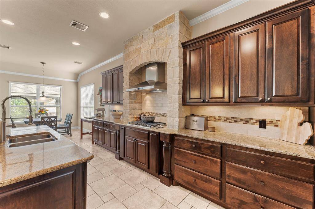 The kitchen is a stunning blend of modern elegance and function. A glass subway tile backsplash creates a refined aesthetic while being highlighted by under-cabinet lighting. The spacious walk-in pantry across from the butler’s pantry offers exceptional storage.  The large sink with industrial sprayer and on-site bottle washer makes clean-up a breeze. A true chef’s kitchen designed for everyday living and grand gatherings alike