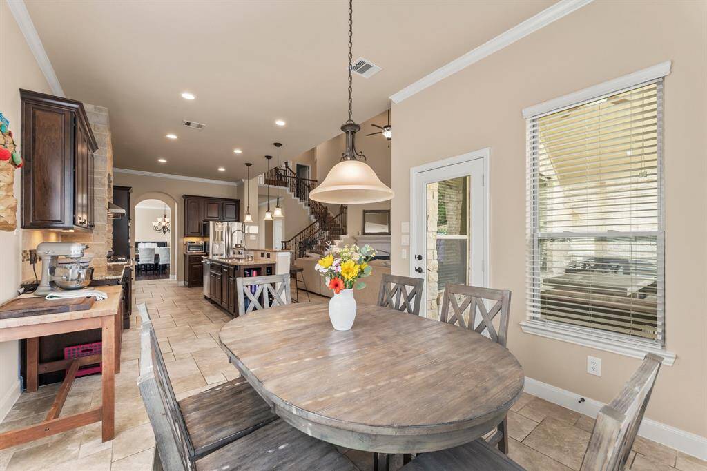 Start your mornings with a cup of coffee or gather for family dinners in this inviting breakfast area! Featuring Versailles tile flooring, sloped ceiling, crown molding, five sunny windows, and a decorative chandelier, this space is filled with natural light. There is also plenty of wall space to add a coffee bar area.