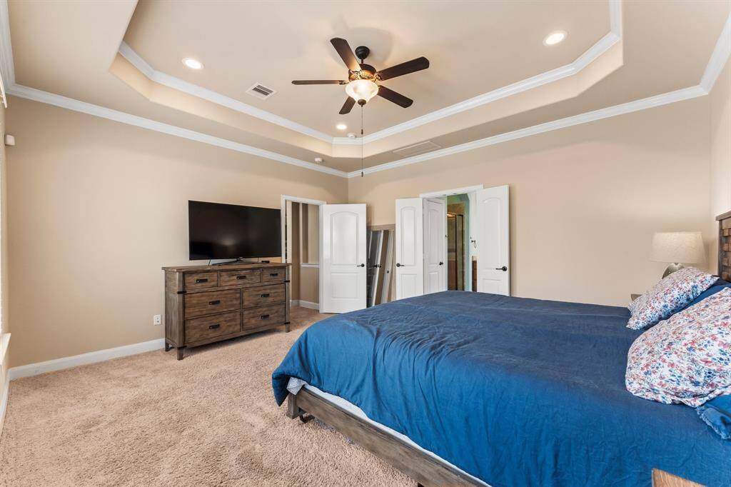 The inviting Owner’s Suite is a private retreat designed for ultimate relaxation. A stunning tray ceiling with crown molding and recessed lighting adds architectural elegance, while lush carpeting  and a stylish ceiling fan with light complete the refined look. Spacious, serene, and beautifully appointed — the perfect escape at the end of the day.