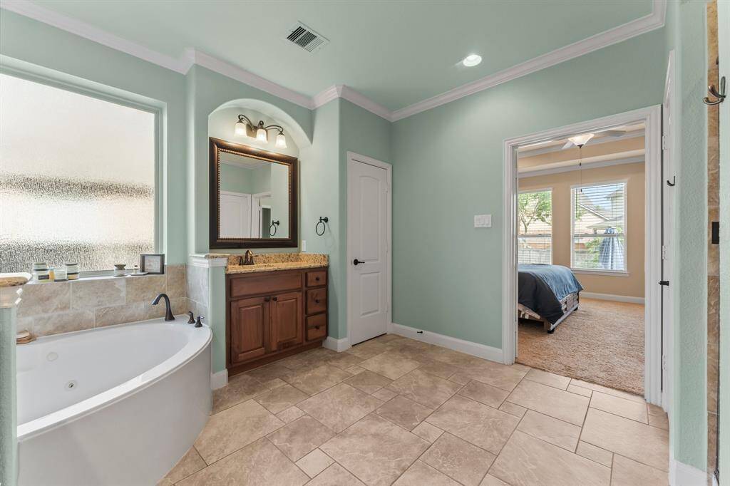 The dual vanities showcase rich cabinetry, gleaming granite counter tops, under-mount sinks, and large framed mirrors.  They each have their own wall in the room to allow plenty of space when getting ready.  Note the arched architectural work surrounding the light fixtures.
