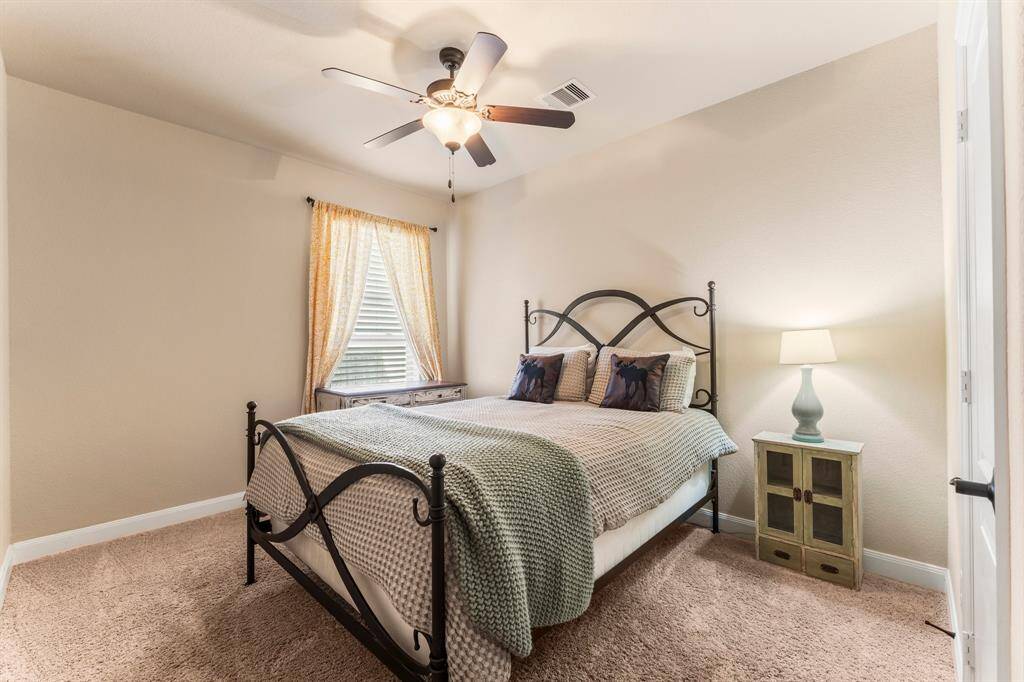 A second downstairs bedroom with access to a full bath offers all the comforts of home, whether for short visits or extended stays. Tucked away in a quiet corner of the house for added privacy, this guest retreat features plush carpeting, a sunlit window with blinds, a spacious walk-in closet, and a lighted ceiling fan for year-round comfort.