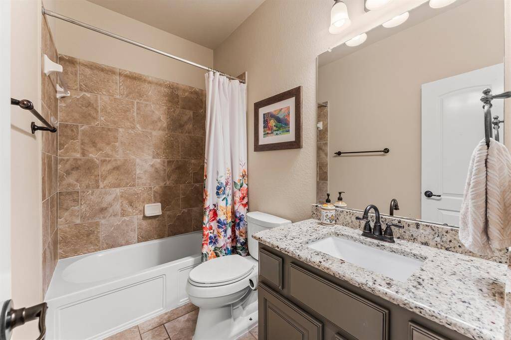 The second full bath on the first floor for guests features Versailles tile flooring, single rectangular undermount sink with granite countertop, hall linen closet, toilet, and tiled shower/tub combo.