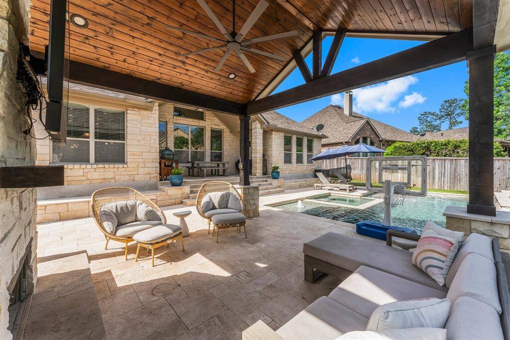 Built-in stone benches surrounding the back of the home offer the perfect spot for relaxing, sunbathing, or gathering with friends after a swim. Stone steps leading to the covered porch boast integrated lighting which not only enhances safety but also adds a warm, inviting glow for evening enjoyment.