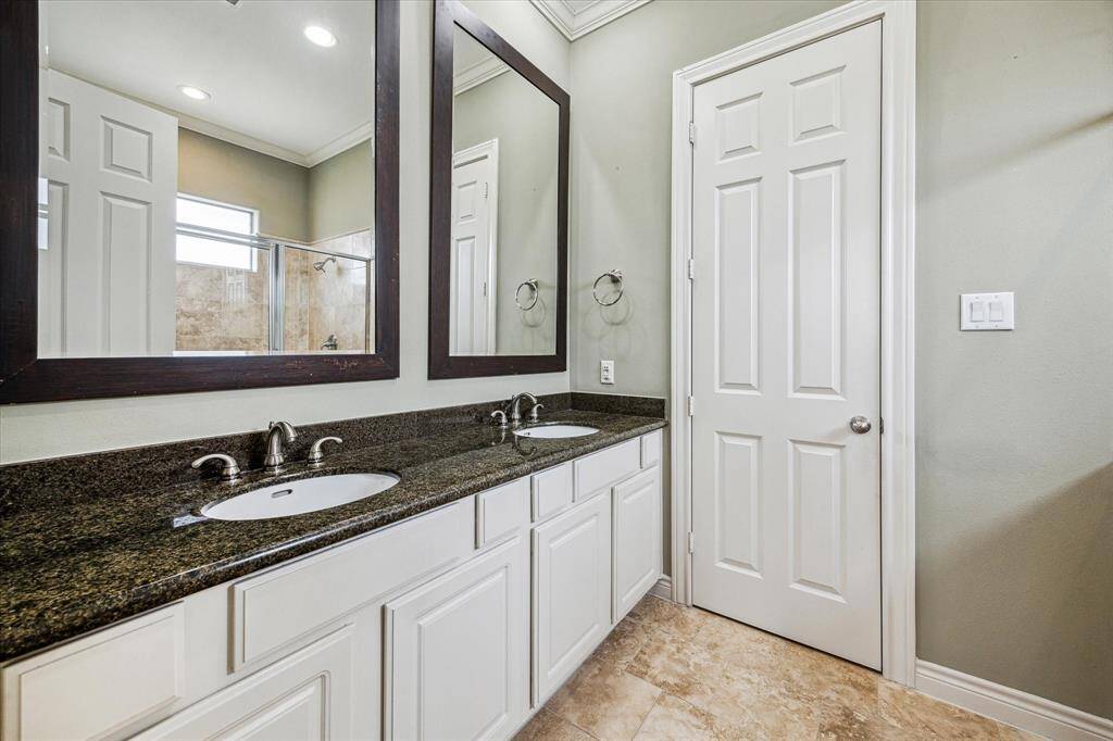 Elegant primary bathroom featuring a double-sink vanity with granite countertops, two large framed mirrors. Enjoy the spa-like feel of the extra-large, wall-to-wall shower and the added privacy of a separate water closet.
