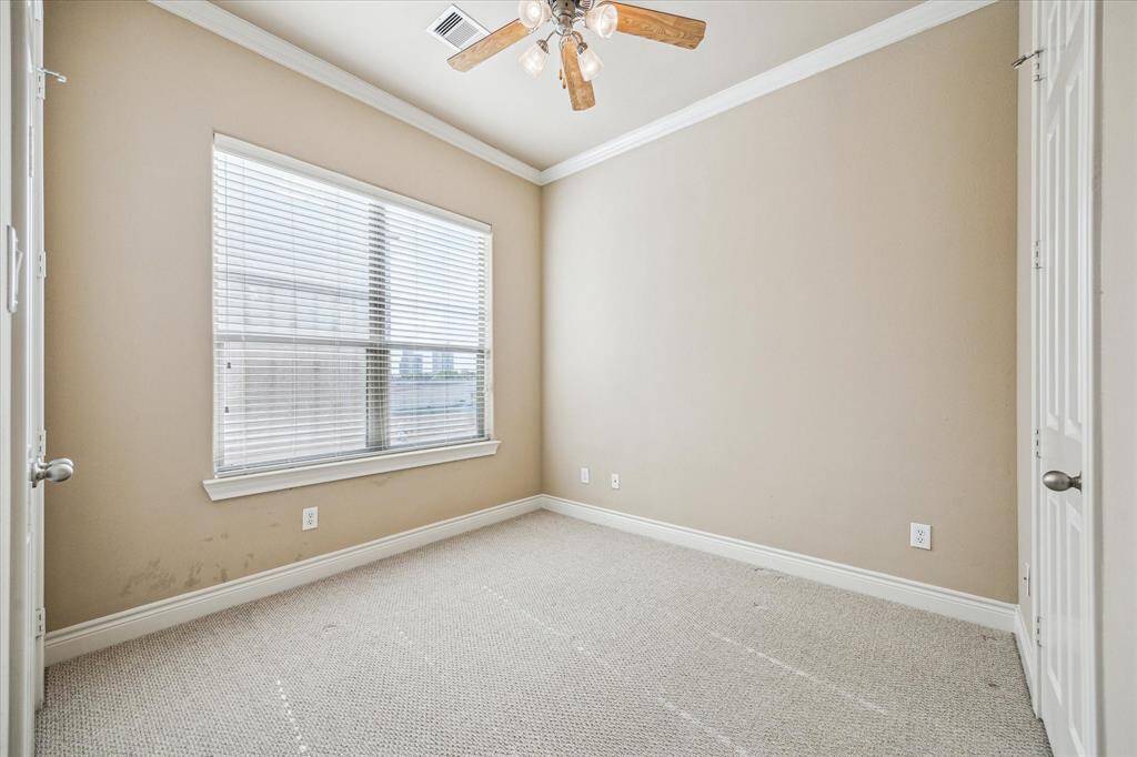 The second of three bedrooms, located on the third floor by the primary, features a large window with abundant natural light and city views. Bedroom has neutral tones and elegant crown molding. This room includes an en-suite bathroom.